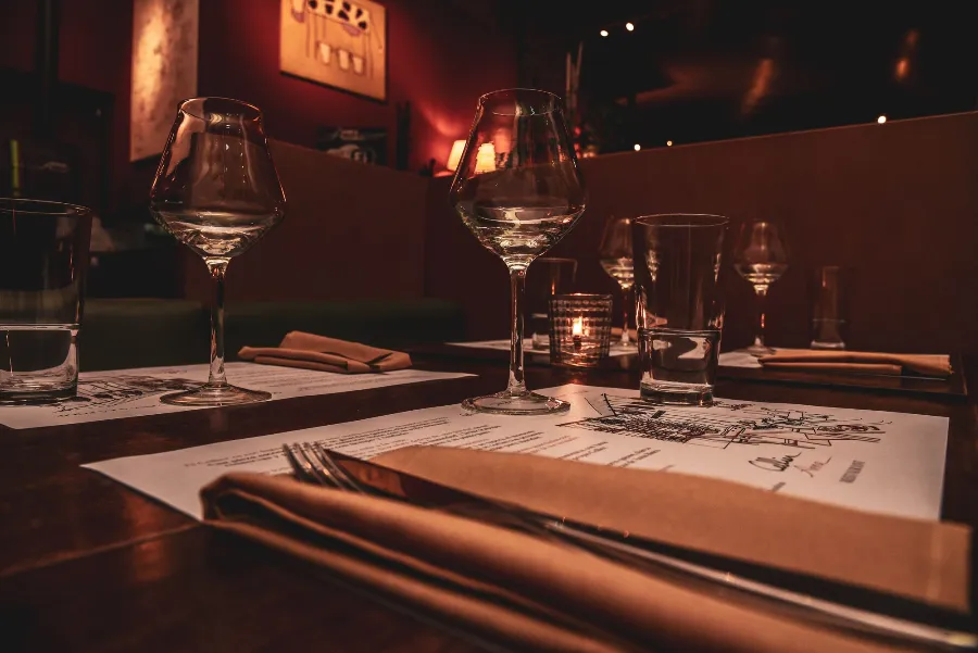A candle-lit restaurant table laid with glasses and a reserved card